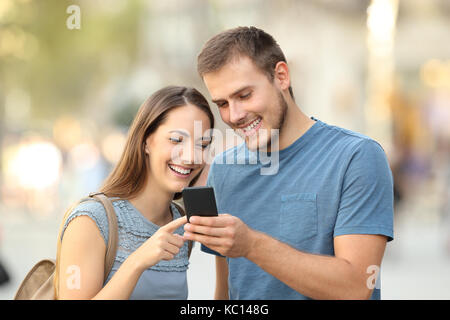 Glückliches Paar suchen auf line Inhalt in einem smart phone stehen draußen auf der Straße