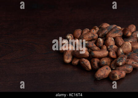 Trockene Kakao samen Haufen Auf dunkelbraunem Holz- Hintergrund Stockfoto