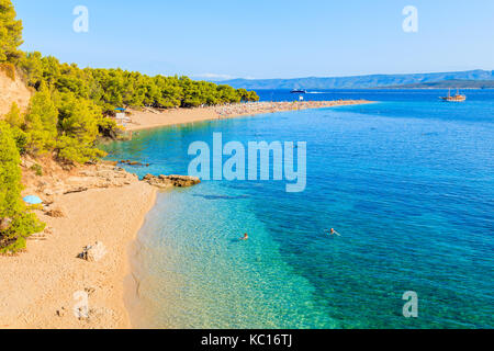 Paar Leute Schwimmen am berühmten Strand Zlatni rat mit schönen Meer Wasser in Bol, Insel Brac, Kroatien Stockfoto