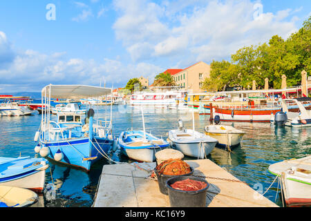 Körbe mit Fischernetzen und traditionelle Boote im Hafen von Bol, Insel Brac, Kroatien Stockfoto