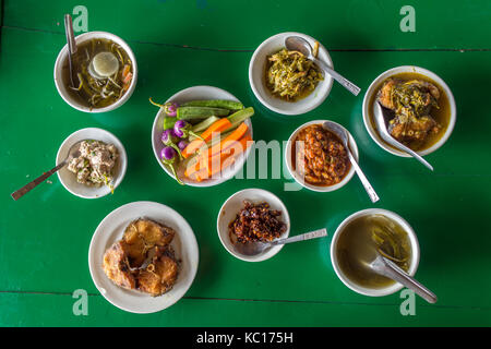 Draufsicht am Tisch mit verschiedenen birmanischen Speisen im lokalen Restaurant in Myanmar. Stockfoto