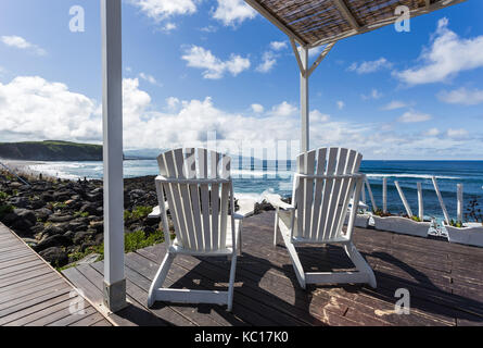 Zwei hölzernen Sessel sitzen auf der Terrasse mit Blick auf den Ozean in Azoren Inseln, São Miguel, Portugal Stockfoto