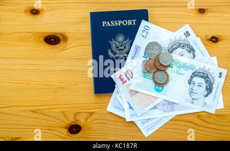 Britisches Geld und einen amerikanischen Pass auf einen hölzernen Tisch Stockfoto