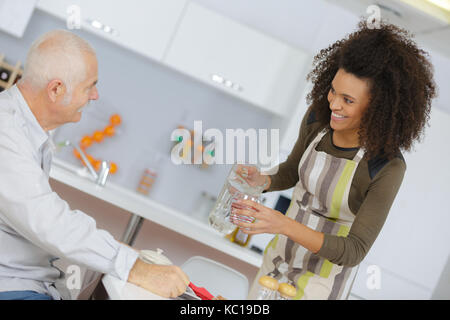 Lächeln auf den Lippen nach Hause Pflegeperson dient Mahlzeit, älterer Mann Stockfoto