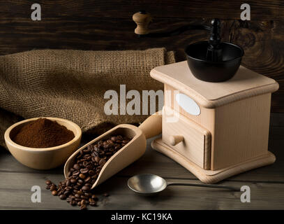 Kaffeebohnen in Holz- Schaufel und gemahlenen Kaffee in Houten mit Kaffee Mahlwerk auf dunklen Holztisch Hintergrund Stockfoto