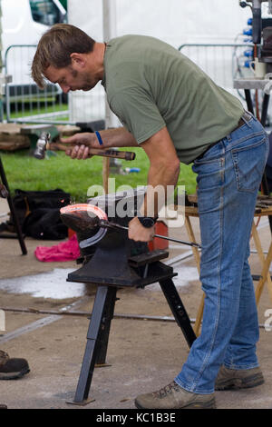 Schmied mit Hammer und Amboss einen heißen Stahl Hufeisen zu gestalten. Stockfoto