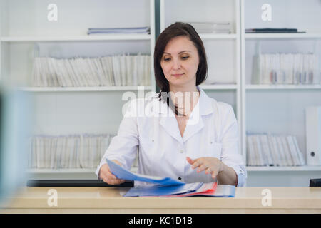 Die jungen praktizierenden Arzt an der Klinik Rezeption arbeiten, ist sie Entgegennehmen von Anrufen und Planen von Terminen Stockfoto