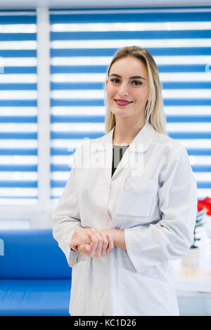 Portrait einer jungen Ärztin trägt einen weissen Mantel im Krankenhaus Büro posing Stockfoto