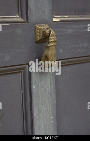 Kleine messing Hand geformt Türklopfer auf einer grauen Tür im französischen Viertel, New Orleans. Stockfoto