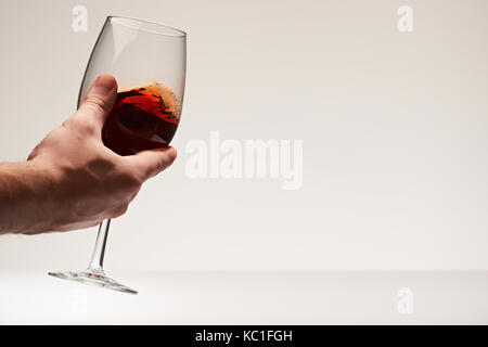 Die Hand schütteln elagant Rotwein Glas isoalted auf weißem Hintergrund Stockfoto