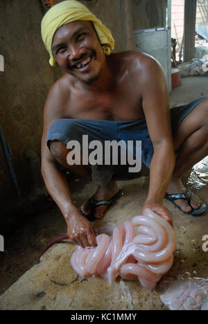 Mann Reinigung Darm von einem Schwein, Angeles, Philippinen. Stockfoto