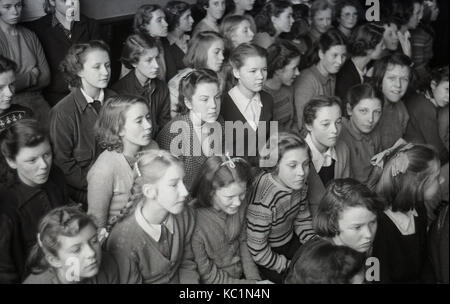 1948, historische, post-ww2 Großbritannien mit Lebensmitteln Rationierung, hier sehen wir Englisch Schule Mädchen sitzen gemeinsam in einer Schule Halle wartet ein Lebensmittel Paket (Geschenk) an die Schule, die der Ausschuß der Australischen Geschenk Paket Regelung zu erhalten. Stockfoto