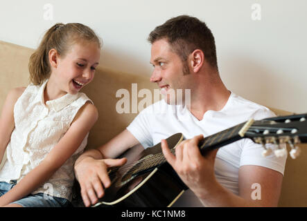 Mein Vater spielt Gitarre für seine Tochter. Stockfoto