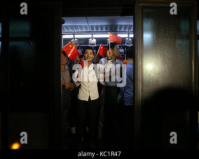 Shanghai, China. 1. Okt 2017. Chinesische Staatsbürger wave kleine chinesische nationale Flaggen auf einen shuttle bus, nachdem Sie am internationalen Flughafen Shanghai Hongqiao in Shanghai angekommen, East China, Oktober 1, 2017. In Antigua und Barbuda geschützten nach Hurrikan Maria verwüstete der Karibischen Insel Dominica, 377 chinesische an Bord von zwei gecharterte Flugzeuge an China Eastern Airlines an Sept. 30 hatte und kam in Shanghai am Sonntag. Credit: Ding Ting/Xinhua/Alamy leben Nachrichten Stockfoto