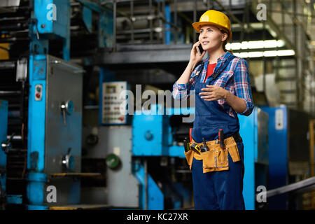 Porträt der jungen Frau in der modernen Fabrik sprechen per Telefon arbeiten zwischen den Reihen von Maschinen, Kopie Raum Stockfoto