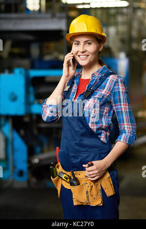 Porträt der jungen Frau in der modernen Fabrik sprechen per Telefon arbeiten und lächelnd Stockfoto