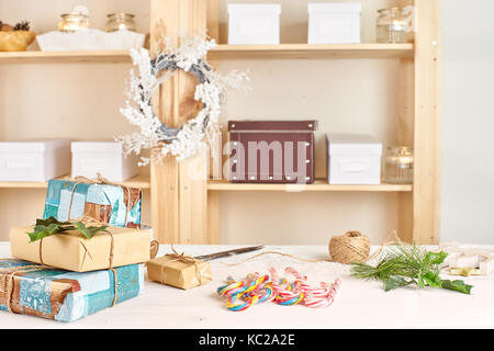 Weiße Holztisch mit Weihnachten Gist, Schere und Süßigkeiten Stockfoto