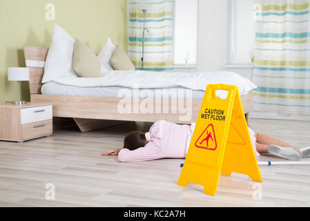 Junge weibliche Haushälterin bewusstlos in der Nähe von nassen Boden Anmelden Hotel Zimmer Stockfoto