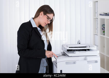 Junge Geschäftsfrau mit Copy Machine im Büro Stockfoto
