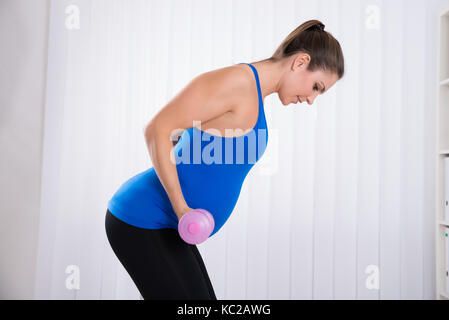 Gerne schwangere Frau, Übung in der Sporthalle Stockfoto