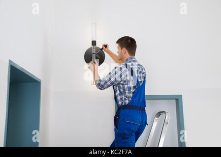 Männliche Elektriker stehen auf trittleiter Instandsetzung Licht Stockfoto