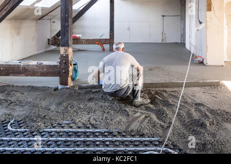 Arbeiter Nivellierung Sand und Zement Estrich auf Fußbodenheizung. Stockfoto