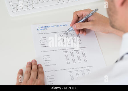 Nahaufnahme der Person Hände füllen Fragebogen mit Stift Stockfoto