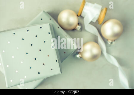 Gestapelte Geschenkboxen in Grau Silber Papier mit Polka Dots Muster gewickelt. Holz- Schieber mit weißem Seidenband, Weihnachten Kugeln auf Stein marmor backgrou Stockfoto