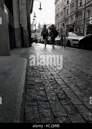 Prag, tschechische Republik - 30. AUGUST 2017; Frauen zu Fuß in der Altstadt Straße in Prag am frühen Abend Licht glitzert auf kopfsteinpflaster als Licht erlischt. Stockfoto