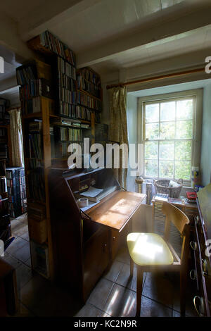 Uriges Haus Innenraum; Zimmer mit Schatten und sonnendurchfluteten Fenstern. Alt fühlen und durcheinandergeworfen Zimmer mit Stühlen, Bücher, CD's und Haus halten. Stockfoto