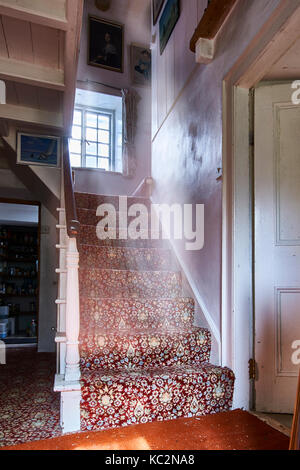 Uriges Haus Innenraum; Zimmer mit Schatten und sonnendurchfluteten Fenstern. Alt fühlen und durcheinandergeworfen Zimmer mit Stühlen, Bücher, CD's und Haus halten. Stockfoto