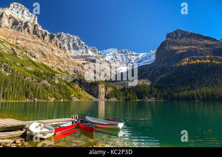 Kanufahrzeuge liegen am Dock des ruhigen Lake O'Hara Water. Malerische Herbstfarben verändern die Landschaft der Canadian Rocky Mountain Peaks BC Yoho National Park Stockfoto