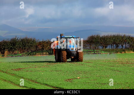 Sprühen das Feld bereit für die nächste Ernte an einem sonnigen Tag mit einem Traktor getragen Spritzmaschine Stockfoto