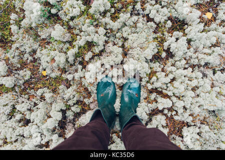 Männliche Beine in Gummistiefel stehen auf moosigen Boden, Ansicht von oben, ungewöhnliche Perspektive Stockfoto