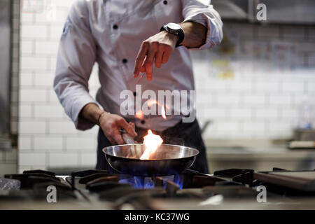 Ein Mann Köche kochen Friteusen in einer Küche Feuer. Stockfoto