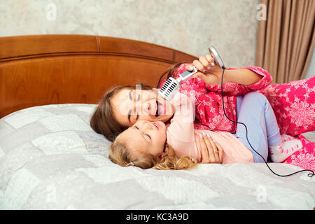 Mutter und Tochter singen gemeinsam Spaß Karaoke Songs im Zimmer. Stockfoto