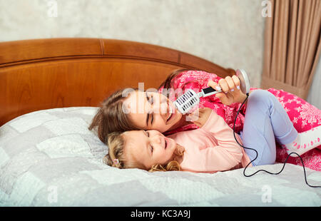 Mutter und Tochter singen gemeinsam Spaß Karaoke Songs im Zimmer. Stockfoto