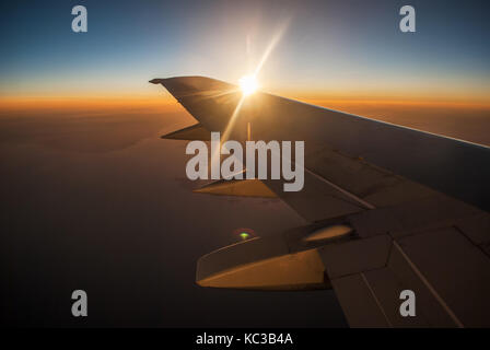 Blick auf den Sonnenaufgang und die Wolken von innen, aus dem Flugzeug Stockfoto