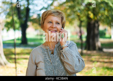 Frau mittleren Alters sprechen auf dem Handy im Park Stockfoto