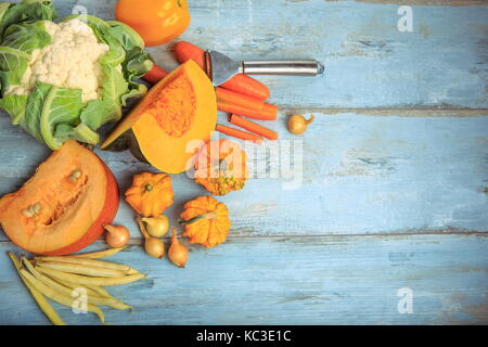 Kürbis Muscat, einfache und dekorative, Karotten, Blumenkohl, grüne Bohnen, Zwiebeln auf einem rustikalen blau Holz- Hintergrund. Gesunde Ernährung, Vegetarische Konzept. Stockfoto