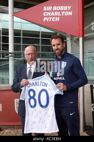 England Manager Gareth Southgate (rechts) und Sir Bobby Charlton (links) Stellen mit einem signierten T-Shirt während einer Enthüllung der neuen Pitch zu seinem 80. Geburtstag während einer Schulung für die Medien Tag in St. George's Park, Burton upon Trent. Stockfoto