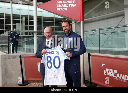 England Manager Gareth Southgate (rechts) und Sir Bobby Charlton (links) Stellen mit einem signierten T-Shirt während einer Enthüllung der neuen Pitch zu seinem 80. Geburtstag während einer Schulung für die Medien Tag in St. George's Park, Burton upon Trent. Stockfoto