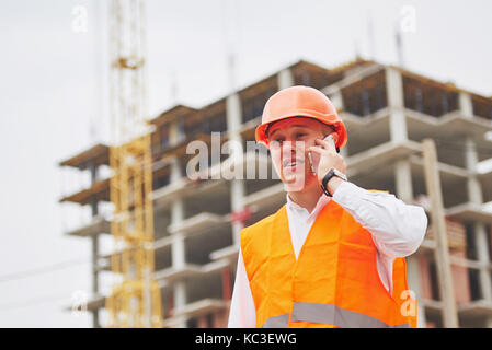 Der junge Architekt trägt einen Schutzhelm auf die Berge Gebäude im Hintergrund Stockfoto