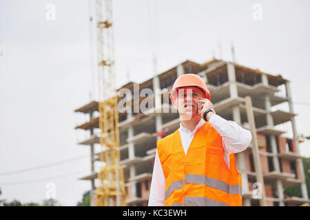 Der junge Architekt trägt einen Schutzhelm auf die Berge Gebäude im Hintergrund Stockfoto