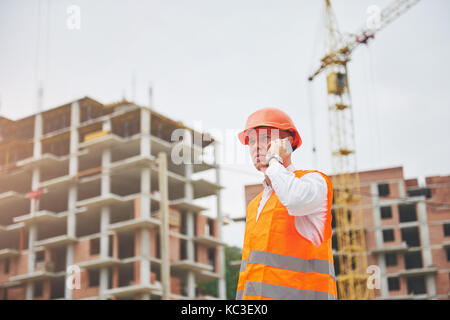 Der junge Architekt trägt einen Schutzhelm auf die Berge Gebäude im Hintergrund Stockfoto