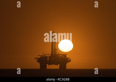 Die Sonne über einem Öl Bohrinsel im Atlantik verankert in Longbeach in der Namib Wüste von Namibia Stockfoto