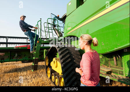 Eine junge weibliche Landwirt Gespräche mit angestellt, um die Hände vor der überschrift heraus zum Ernten von Weizen auf der Farm der Familie in Breckenridge, Colorado, wo sie wachsen 1. Stockfoto