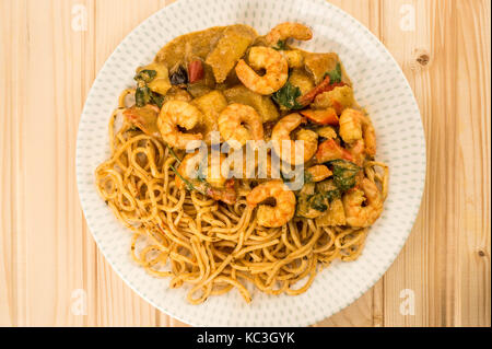 Sri Lanka Style King Prawn Curry mit Nudeln gegen eine leichte Kiefer Holz Hintergrund Stockfoto