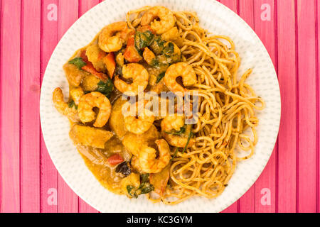 Sri Lanka Style King Prawn Curry mit Nudeln gegen eine Rosa Holz- Hintergrund Stockfoto