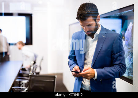 Portrait der junge Geschäftsmann mit Mobiltelefon Stockfoto
